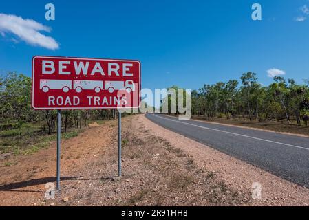 A red road sign warns of Road Trains on the road beside the highway near Darwin in the Northern Territory in Australia Stock Photo