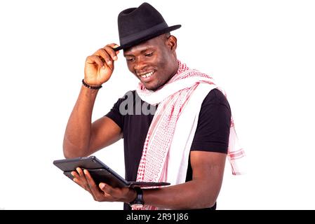 young man wearing hat and scarf, holding digital tablet smiling. Stock Photo