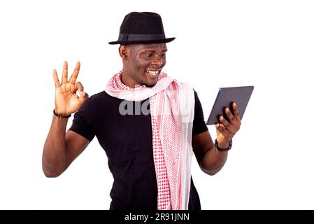handsome young man holding digital tablet and doing okay gesture with fingers smiling. Stock Photo