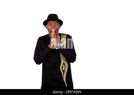 portrait of a handsome young man holding both hands together near the mouth. Stock Photo