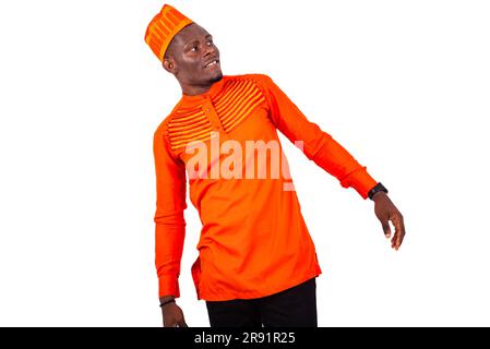 a handsome businessman in orange clothes standing against white background and leaning to look at something smiling Stock Photo