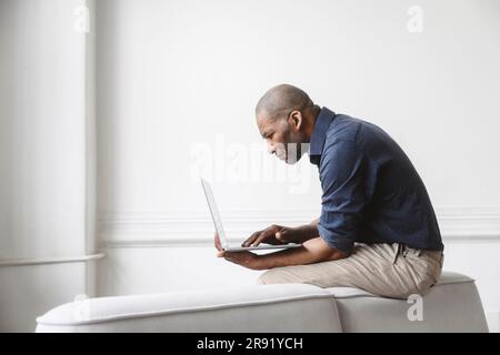 Businessman working on laptop sitting on sofa at home Stock Photo