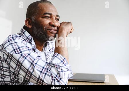 Thoughtful businessman leaning on elbow at table Stock Photo