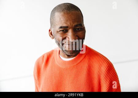 Smiling mature man wearing orange sweater Stock Photo