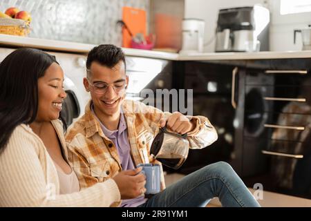 Man serving coffee to woman in kitchen at home Stock Photo