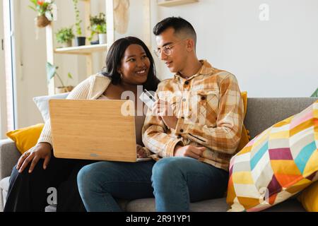 Couple doing online shopping using credit card and laptop at home Stock Photo