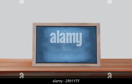 A blank chalkboard on a wooden table in front of a white background Stock Photo