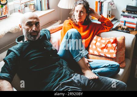 Multiracial couple sitting on sofa at home Stock Photo