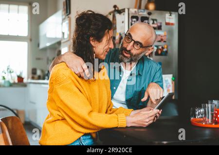 Man pointing at tablet PC held by woman sitting at home Stock Photo