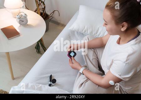 Woman checking blood sugar level at home Stock Photo