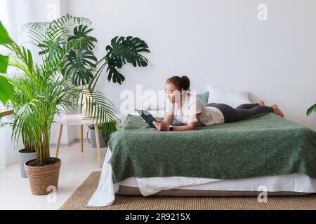 Young woman with diabetes using tablet PC lying on bed at home Stock Photo