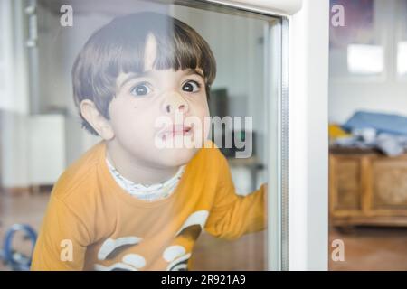 Boy pressing nose against window Stock Photo