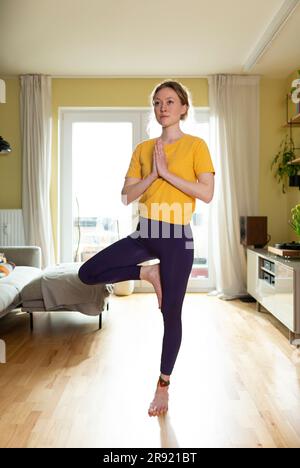 Young woman practicing tree pose at home Stock Photo