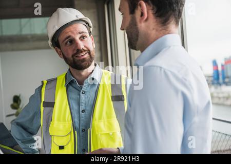 Building contractor discussing with architect at site Stock Photo
