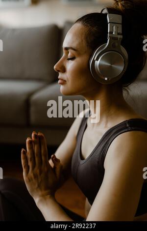 Woman with headphones meditating at home Stock Photo