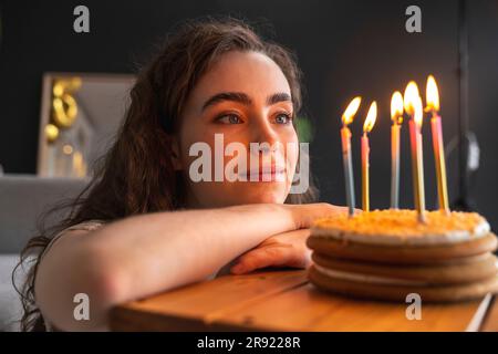 Young woman looking at cake celebrating birthday at home Stock Photo