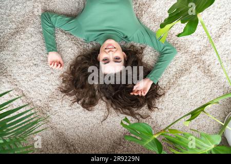 Smiling young woman lying on rug at home Stock Photo