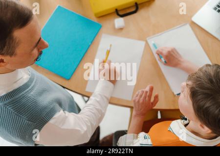 Colleagues standiung at desk talking taking notes on papers Stock Photo