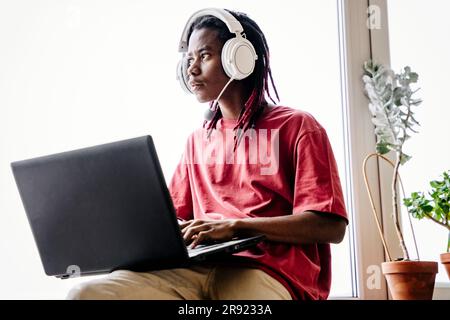 Thoughtful man with headset and laptop at home Stock Photo