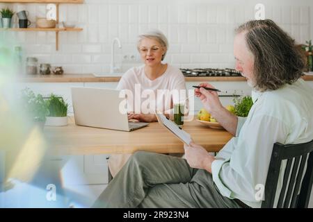 Man discussing with nutritionist working on laptop at home Stock Photo