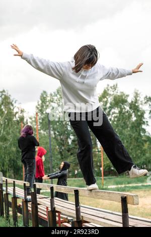 Carefree girl balancing on bench at park Stock Photo