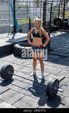 Woman standing in front of barbell weights at rooftop gym Stock Photo