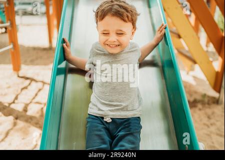 Cheerful boy having fun on slide in playground Stock Photo