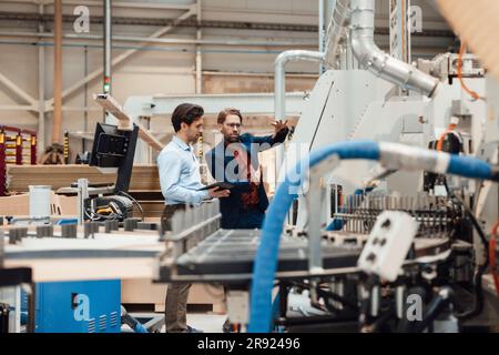 Mature businessman explaining and having discussion with colleague at industry Stock Photo