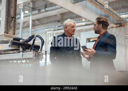 Mature businessman having discussion with colleague at factory Stock Photo
