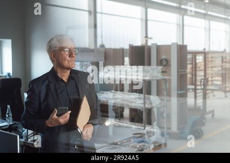 Contemplative senior businessman seen through glass Stock Photo