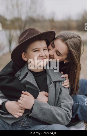 Mother embracing happy son sitting on field Stock Photo