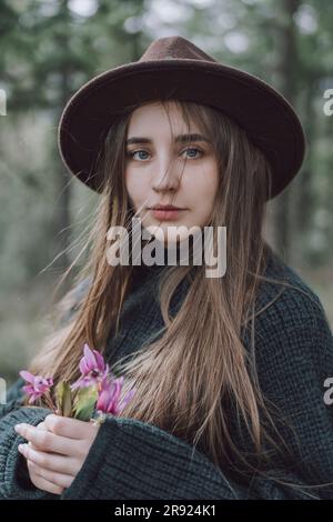 Beautiful young woman with long hair holding flowers Stock Photo