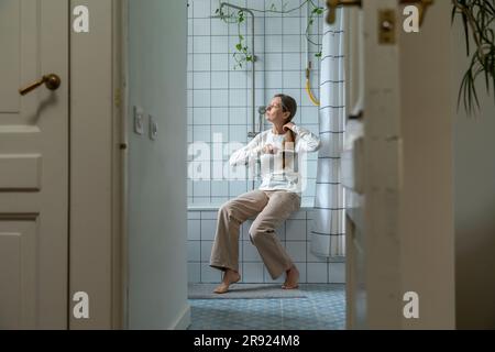 Mature woman brushing hair in bathroom at home Stock Photo