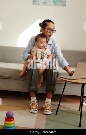 Freelancer father working on laptop sitting with daughter at home Stock Photo