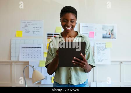 Happy freelancer using tablet PC at home office Stock Photo