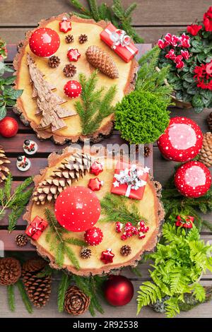 Winter plants, pine cones, Christmas decorations, wooden coasters and presents on table Stock Photo