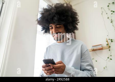 Smiling man using smart phone at home Stock Photo