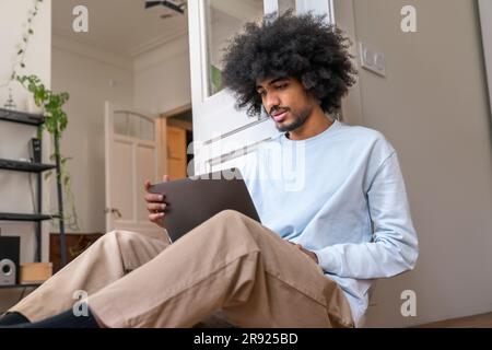 Freelancer working on laptop sitting on floor at home Stock Photo