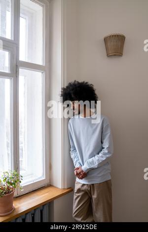 Man looking out of window standing at home Stock Photo