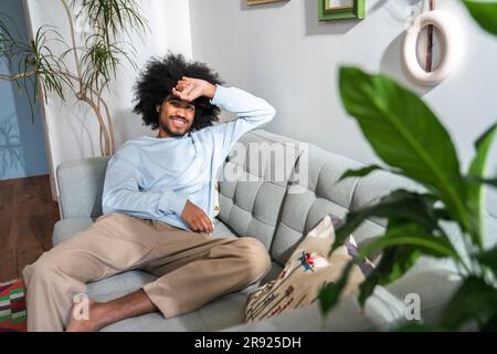 Smiling man sitting on sofa at home Stock Photo