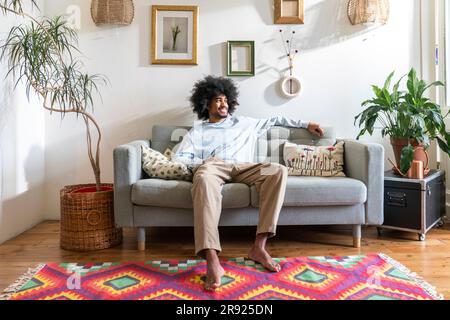 Smiling man relaxing on sofa at home Stock Photo