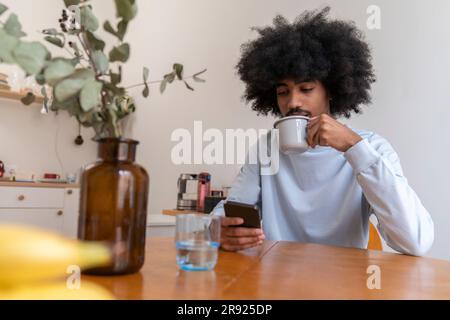 Man drinking coffee and using smart phone at home Stock Photo
