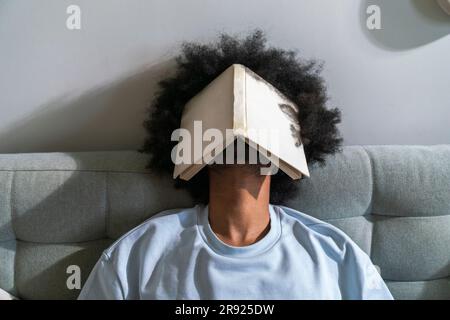 Man with curly hair sleeping on sofa at home Stock Photo