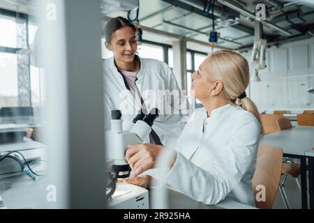 Smiling scientist having discussion with colleague in laboratory Stock Photo