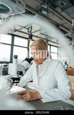 Senior scientist working with microscope in laboratory Stock Photo
