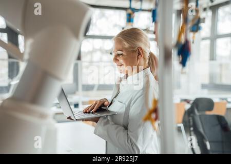 Smiling senior scientist using laptop in laboratory Stock Photo