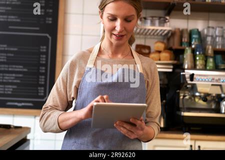 Coffee shop owner using tablet PC in cafe Stock Photo
