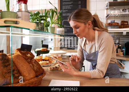 Coffee shop owner wearing apron using tablet PC Stock Photo
