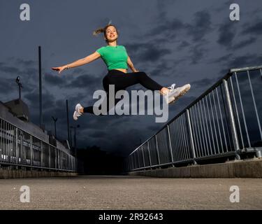 Smiling young athlete jumping on river weir Stock Photo