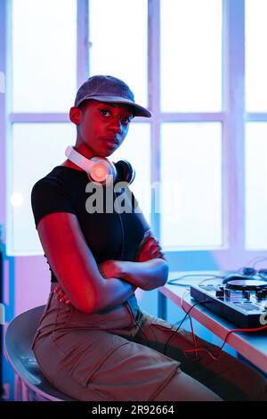 Young Dj wearing cap sitting with arms crossed Stock Photo